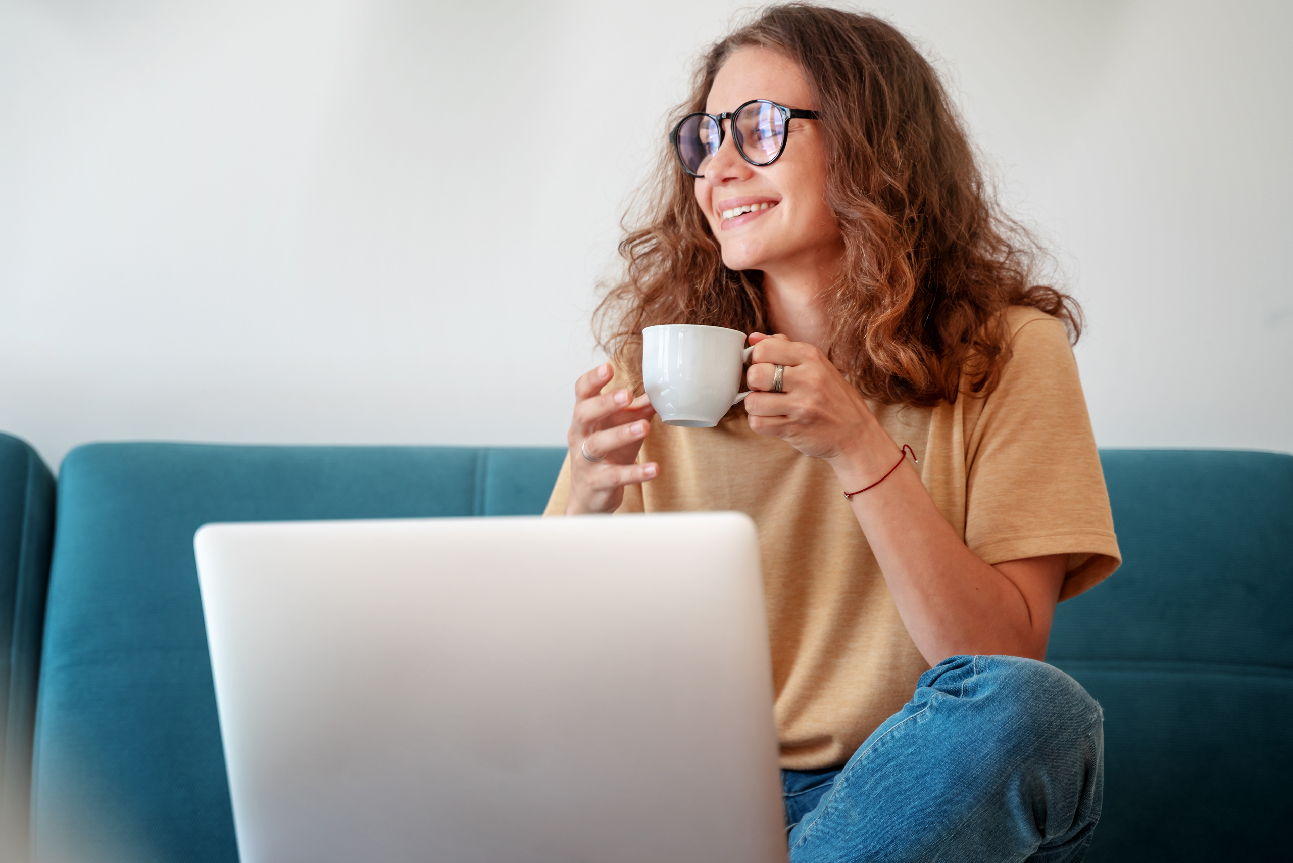 Woman with ADHD smiling while drinking coffee and using a laptop.
